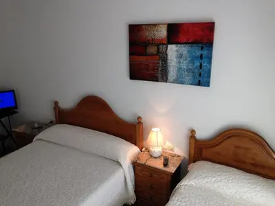 a bedroom with two beds and a lamp on a night stand at Pensión Glorioso II in Picaraña
