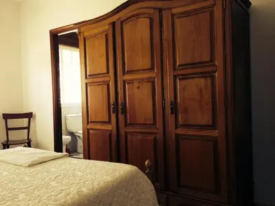 a bedroom with a large wooden cabinet next to a bed at Pensión Glorioso II in Picaraña