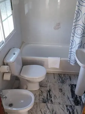 a bathroom with a toilet and a tub and a sink at Pensión Glorioso II in Picaraña