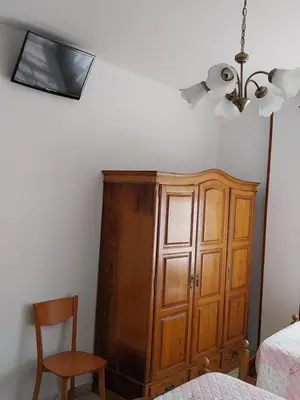 a bedroom with a wooden cabinet and a chair at Pensión Glorioso II in Picaraña