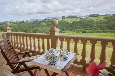 a table with a tea set on a balcony at Camino de las Mimosas: relax en un entorno idílico in Folgueras