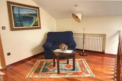a living room with a blue chair and a table at Camino de las Mimosas: relax en un entorno idílico in Folgueras