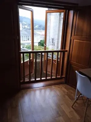 a room with a balcony with a large window at O Picho: apartamento céntrico. in Puentedeume