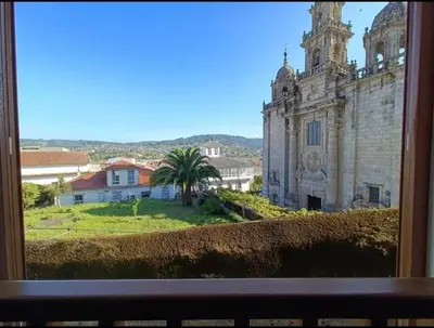 a window view of an old building with a palm tree at O Picho: apartamento céntrico. in Puentedeume
