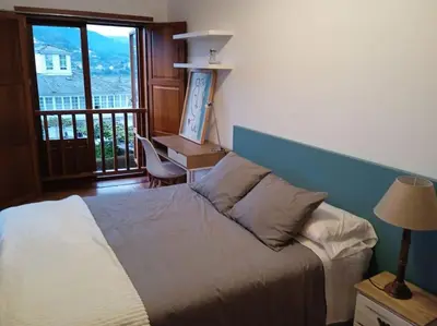 a bedroom with a bed and a desk and a window at O Picho: apartamento céntrico. in Puentedeume