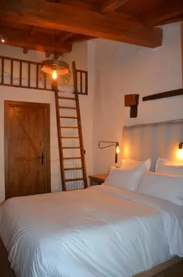 a bedroom with a large white bed and a ladder at Casa Sapita in Villafranca del Bierzo