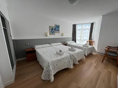 a bedroom with two beds and a large window at Pensión O Castelo in Palas de Rei