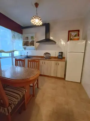 a kitchen with a table and a white refrigerator at Sobre el Puerto in Viveiro