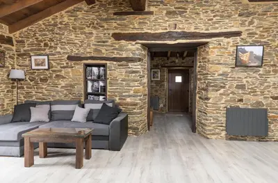 a living room with a couch and a stone wall at Casa Rural Lar de Sanxes in A Pontenova