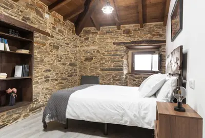 a bedroom with a brick wall and a bed at Casa Rural Lar de Sanxes in A Pontenova