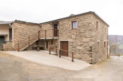 a stone house with a staircase on the side of it at Casa Rural Lar de Sanxes in A Pontenova