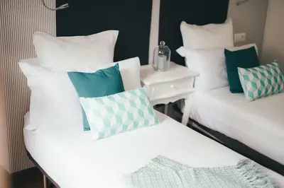 a room with two beds with pillows and a table at Apartamentos Aurelia Antica in Santiago de Compostela