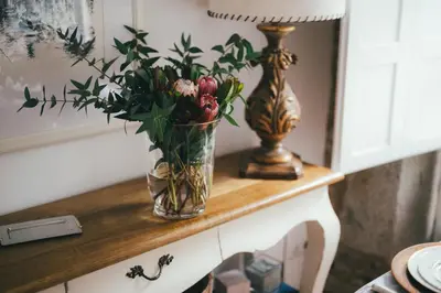 a vase of flowers on a table with a lamp at Apartamentos Aurelia Antica in Santiago de Compostela