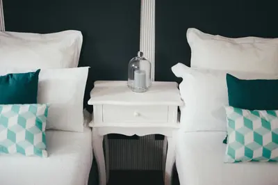 a white bed with a night stand next to a bed with pillows at Apartamentos Aurelia Antica in Santiago de Compostela