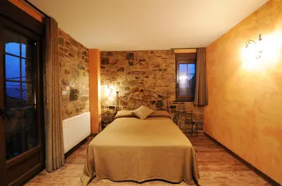 a bedroom with a bed and a stone wall at Hotel Rural La Casa del Peregrino in El Acebo de San Miguel