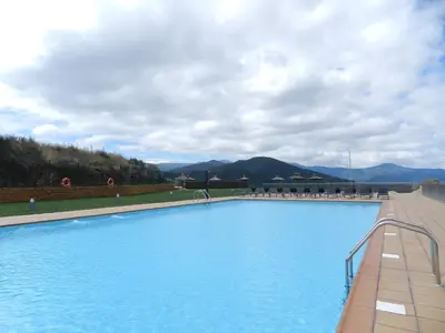 a large blue swimming pool with mountains in the background at Hotel Rural La Casa del Peregrino in El Acebo de San Miguel