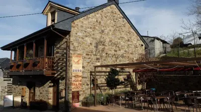 a brick building with a balcony and tables and chairs at Hotel Rural La Casa del Peregrino in El Acebo de San Miguel
