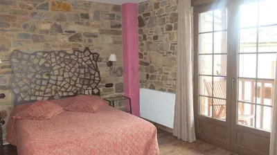 a bedroom with a bed and a stone wall at Hotel Rural La Casa del Peregrino in El Acebo de San Miguel