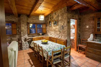 a dining room with a table and a stone wall at Casa Rural Anita in Cabrillanes