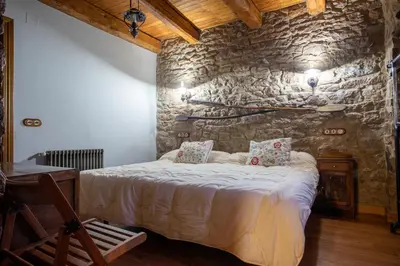 a bedroom with a bed with a stone wall at Casa Rural Anita in Cabrillanes