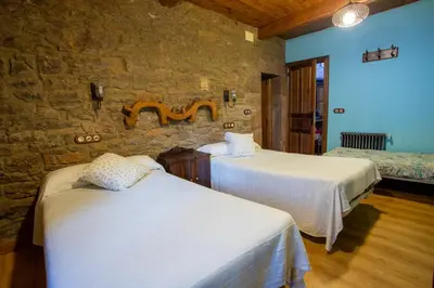 a bedroom with two beds and a stone wall at Casa Rural Anita in Cabrillanes