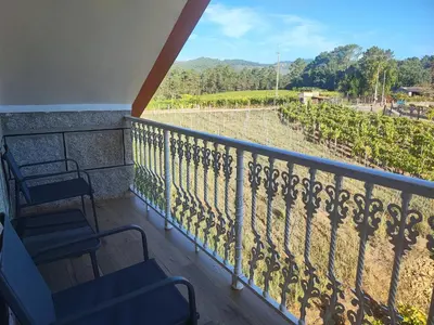 a balcony with chairs and a view of a vineyard at CASA DO AVÒ in Castrelo de Miño