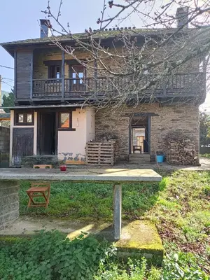 a house with a balcony and a table in front of it at CASA DA RIBEIRA in Quiroga