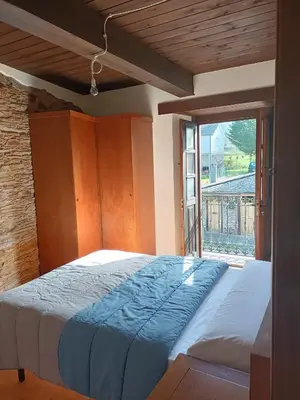 a bed in a room with a large window at CASA DA RIBEIRA in Quiroga