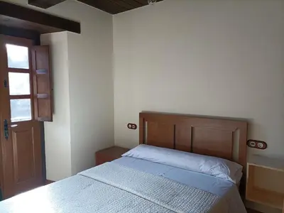 a bedroom with a bed with a wooden headboard and a window at CASA DA RIBEIRA in Quiroga