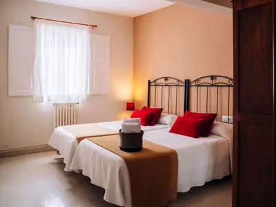 a bedroom with two beds with red pillows and a table at Hospedaje Ramos in Santiago de Compostela
