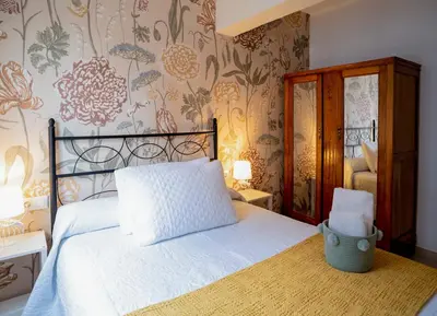 a bedroom with a bed and a wall with flowers at Hospedaje Ramos in Santiago de Compostela