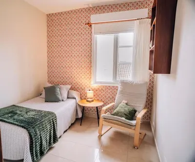 a bedroom with a bed and a chair and a window at Hospedaje Ramos in Santiago de Compostela