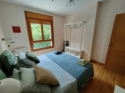 a bedroom with a blue bed and a window at Ventana al Paraíso del Oso - Somiedo. Window to Bear Paradise - Somiedo in Pola de Somiedo