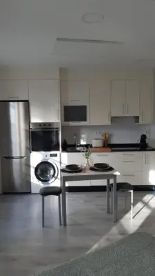 a white kitchen with a table and a refrigerator at Apartamentos SARABIA LOFT in Ourense
