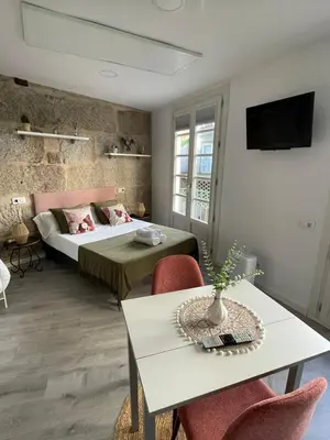 a bedroom with a bed and a table with chairs at Apartamentos SARABIA LOFT in Ourense