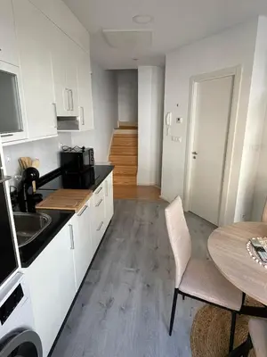a kitchen with white cabinets and a table and a dining room at Apartamentos SARABIA DARRIBA in Ourense