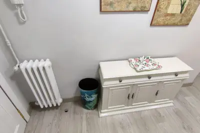 a small white cabinet next to a radiator and a trash can at Piso Turístico Avda del Castillo in Ponferrada