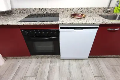 a kitchen with a stove and a white dishwasher at Piso Turístico Avda del Castillo in Ponferrada
