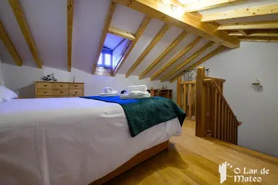 a bedroom with a large bed in a room with wooden ceilings at O Lar de Mateo in Monforte de Lemos