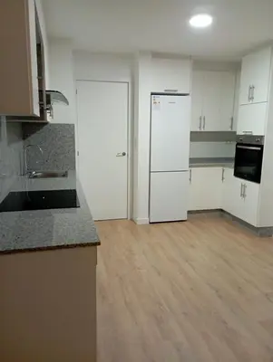 a kitchen with white cabinets and a wooden floor at Pardiñas 36 in Santiago de Compostela