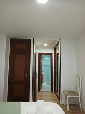 a bedroom with a bed and a chair and a door at Pardiñas 36 in Santiago de Compostela