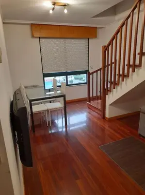 a living room with a dining room table and stairs at Alojamiento entero cerca de Santiago de Compostela in A Coruña