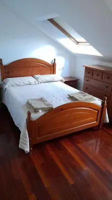 a bedroom with a wooden bed with a wooden floor at Alojamiento entero cerca de Santiago de Compostela in A Coruña