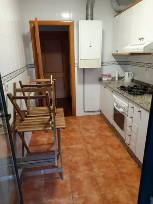 a kitchen with two chairs and a table and a stove at Alojamiento entero cerca de Santiago de Compostela in A Coruña