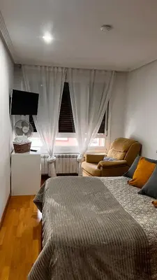 a bedroom with a bed and a couch and a television at Acogedor piso céntrico in Lugo