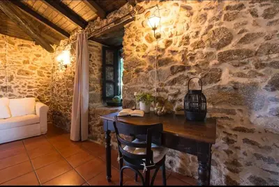 a room with a wooden table and a stone wall at Casa con Piscina *Ribeira Sacra* in Ferreira de Panton