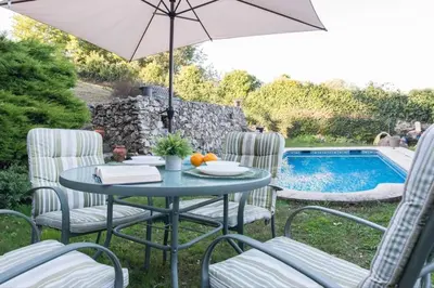a table with chairs and an umbrella next to a pool at Casa con Piscina *Ribeira Sacra* in Ferreira de Panton