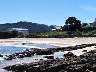 a beach with rocks in the water and houses at Neboa in Viveiro