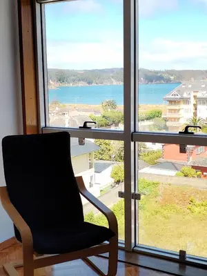 a chair in front of a window with a view of the ocean at Neboa in Viveiro