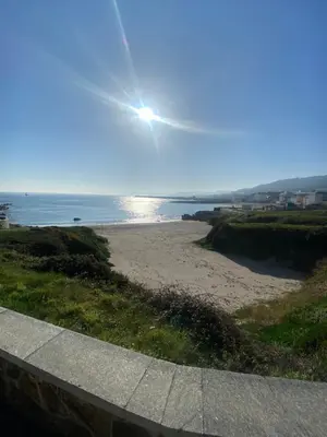 a view of a beach with the sun in the sky at Apartamentos LAMAROSA -LAS PLAYAS in Burela de Cabo
